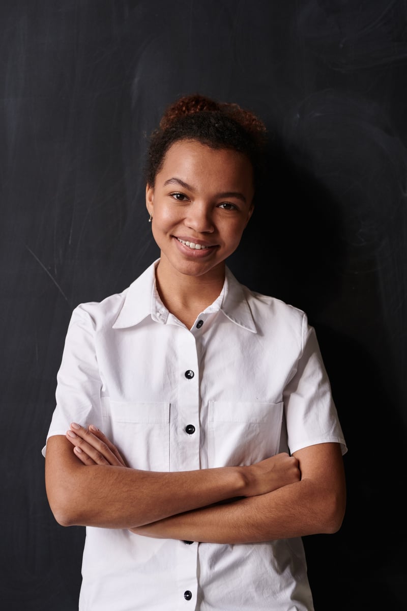 Woman in White Button-up Shirt Standing Beside Black Wall Paint While Smiling